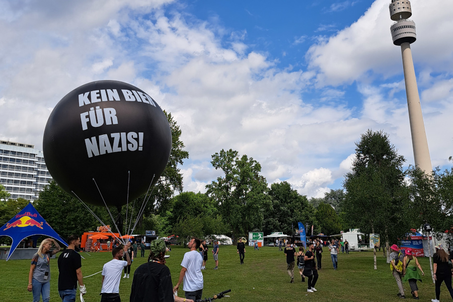 Besucher:innen des Juicy Beat Festivals mit Ballon mit der Aufschrift "Kein Bier für Nazis"